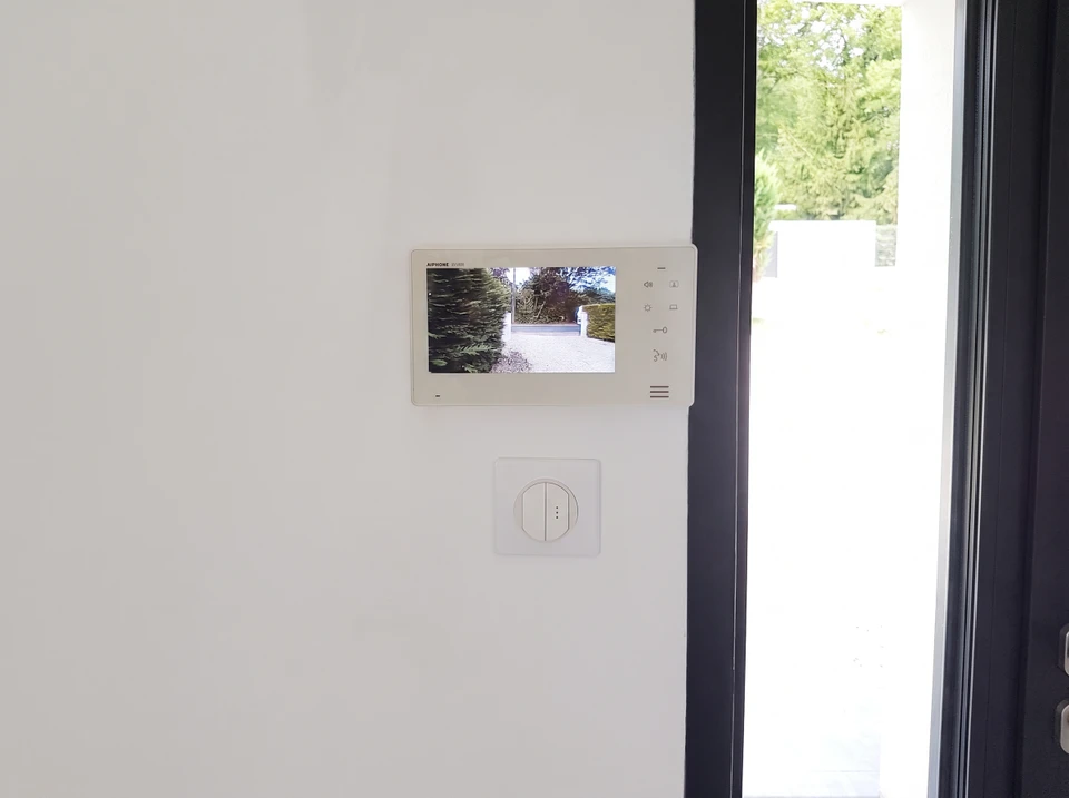 Borne de recharge pour véhicule électrique Schneider Electric, montée sur mur de briques blanches en extérieur