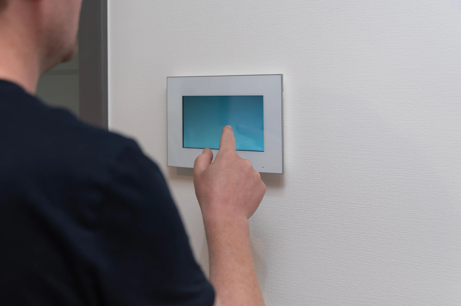 Main tenant un smartphone affichant une interface d'application domotique "HOME AUTOMATION" avec icônes de contrôle : éclairage, température, sécurité, caméra surveillance, serrure connectée